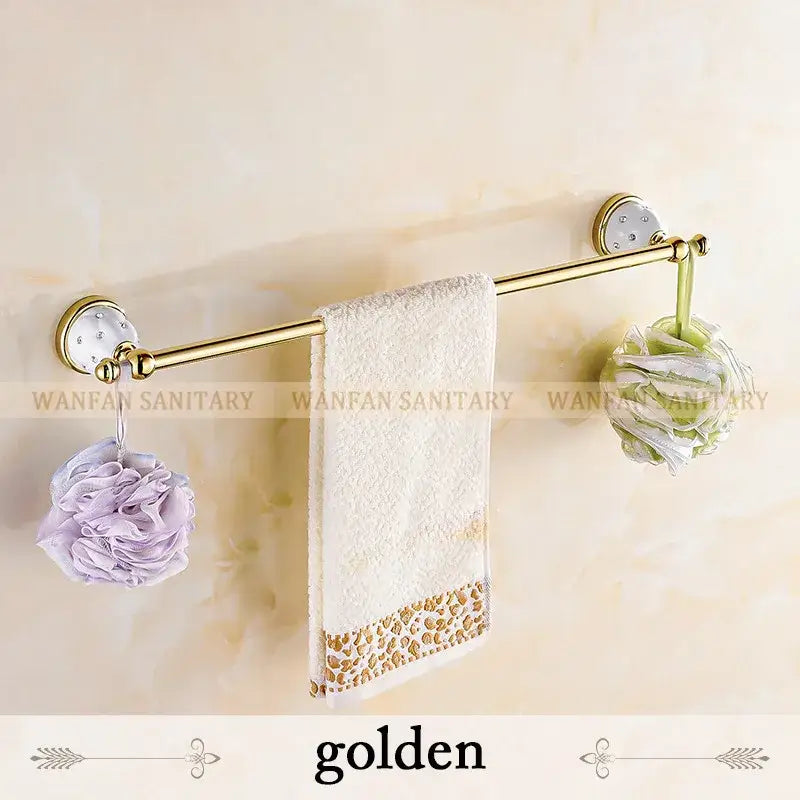 Golden towel rack with ceramic wall mounts and ornate finials holding white towel with gold leopard trim decorbites crystal brass gold bathroom accessory