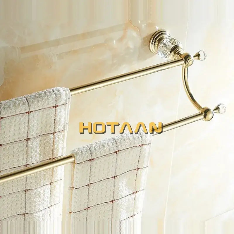 Gold-toned crystal double towel bar holding white checkered towels for elegant bathroom organization