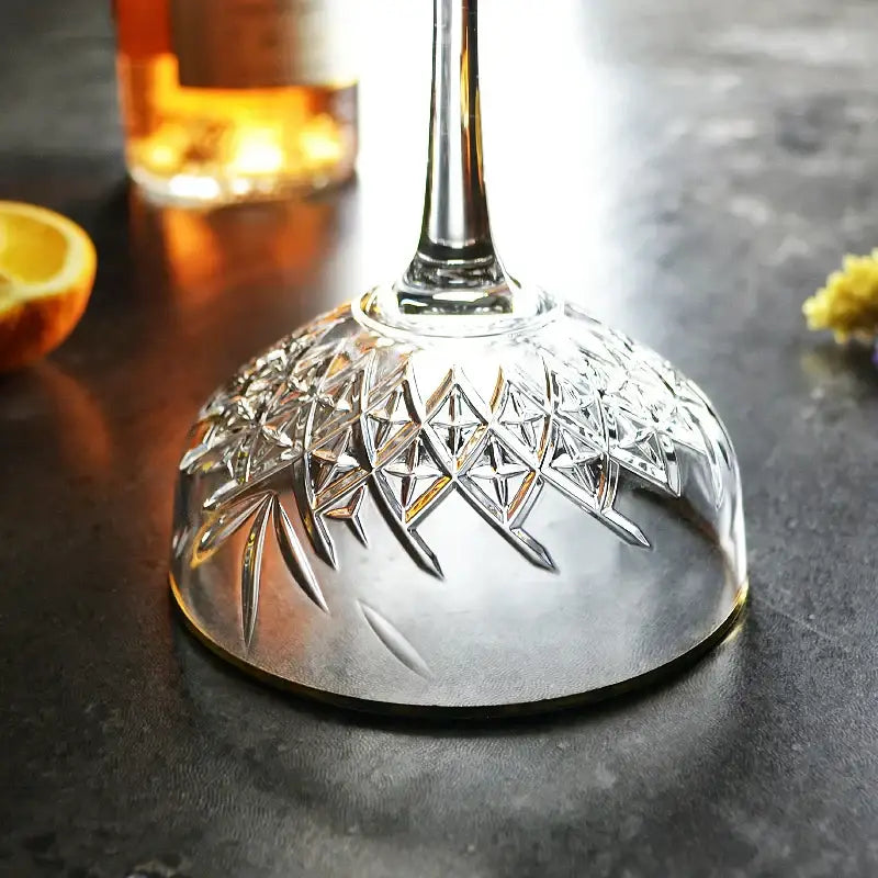 A clear crystal gold rim coupe glass with intricately cut pattern base and slender stem for elegant decorbites gold rim dining