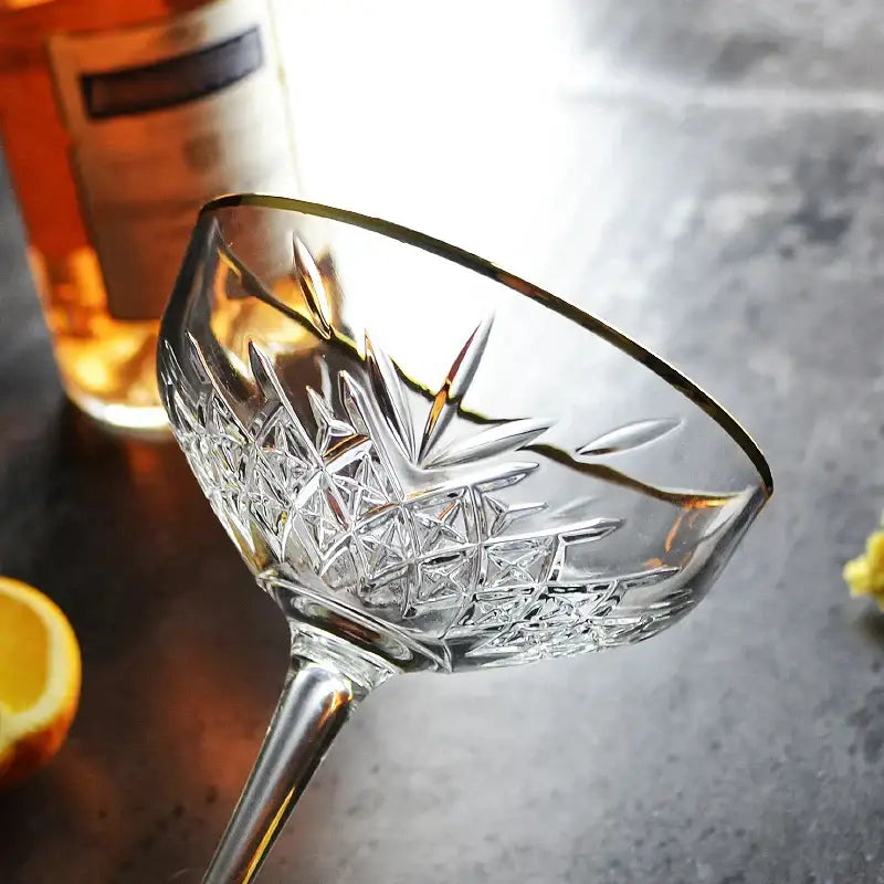 A clear crystal gold rim coupe glass with intricate cut pattern and long stem from decorbites gold rim collection