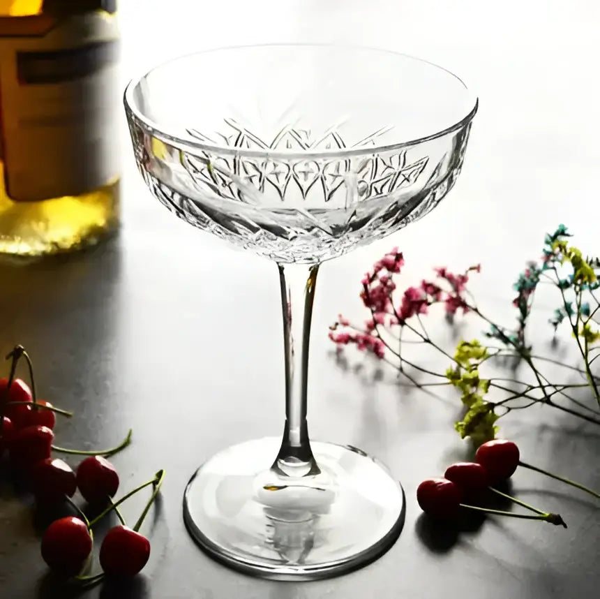 A clear crystal gold rim coupe glass with intricate diamond cut pattern and slender stem for elegant dining decorbites gold rim