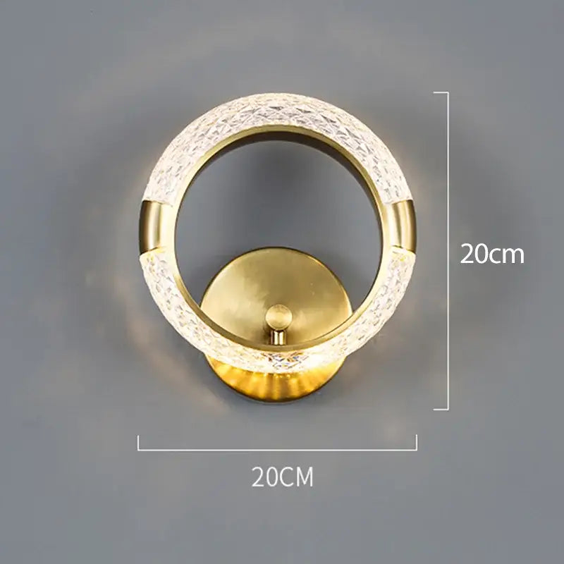 Gold-toned decorbites crystal nordic wall sconce featuring a textured crystal ring and polished brass base for bedroom light