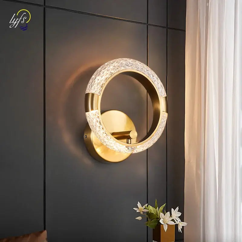 Gold-toned decorbites crystal nordic wall sconce with textured crystal-encrusted ring and polished brass mount for bedroom use
