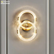 Gold-toned decorbites crystal nordic wall sconce with two interlocking rings and sparkling crystal accents for bedroom light