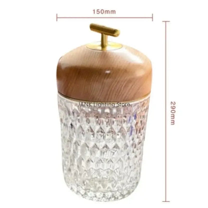 Crystal table lamp with a clear diamond-cut glass jar and light brown wooden lid with brass handle for bedroom use
