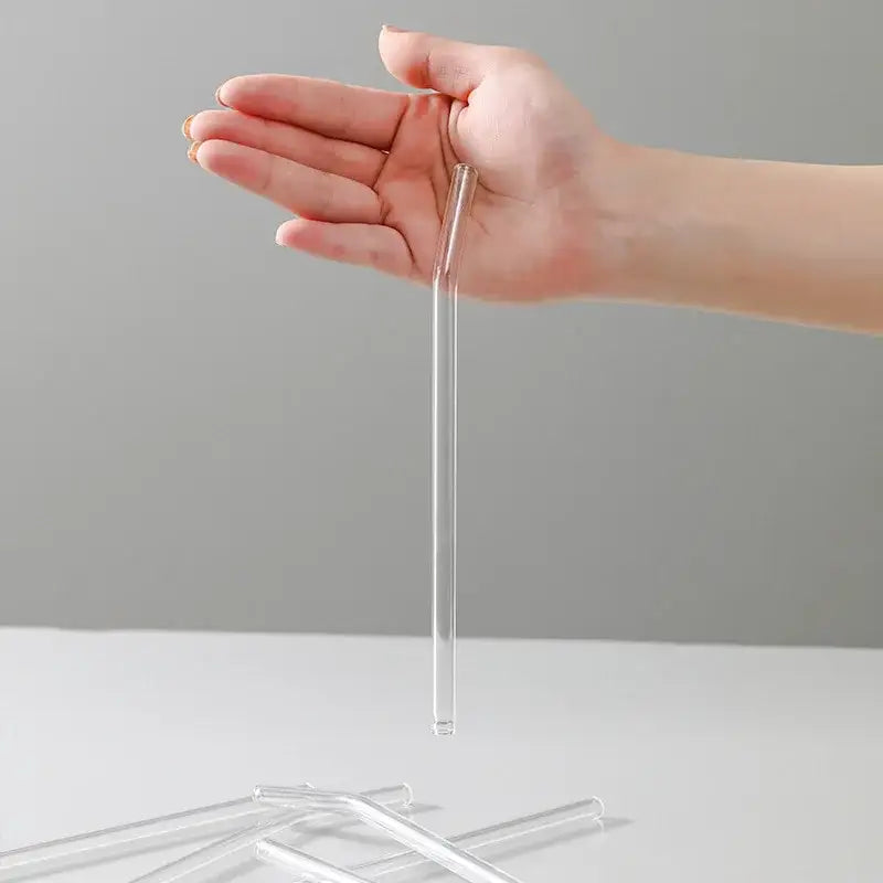 Clear glass curved tip straw held in open palm made by decorbites glass straws for reusable eco friendly kitchen use