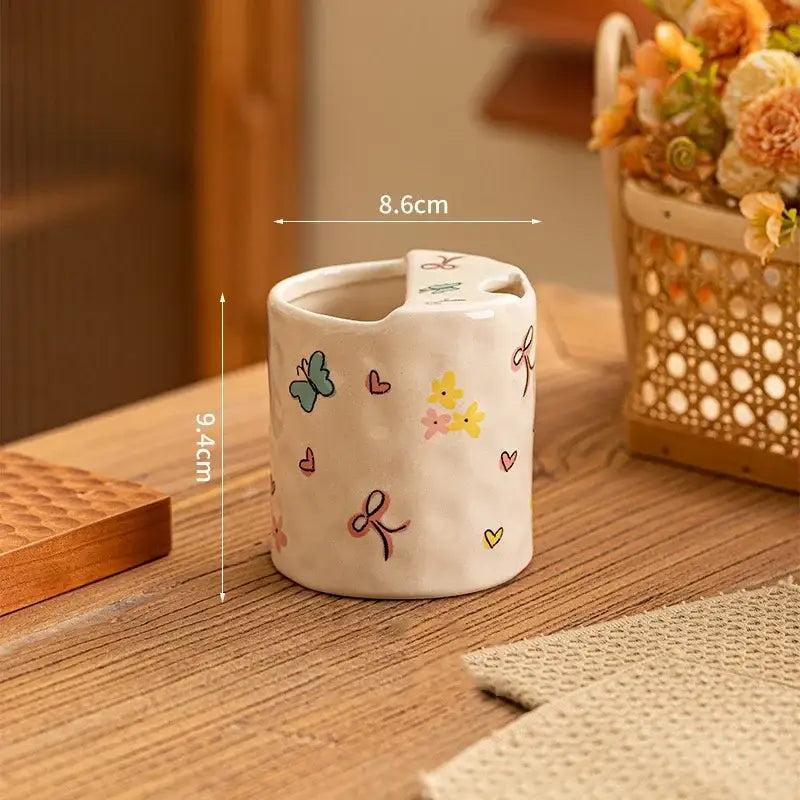 A charming off-white ceramic toothbrush holder with pastel butterfly heart and bow decals complementing decorbites bowknot pattern