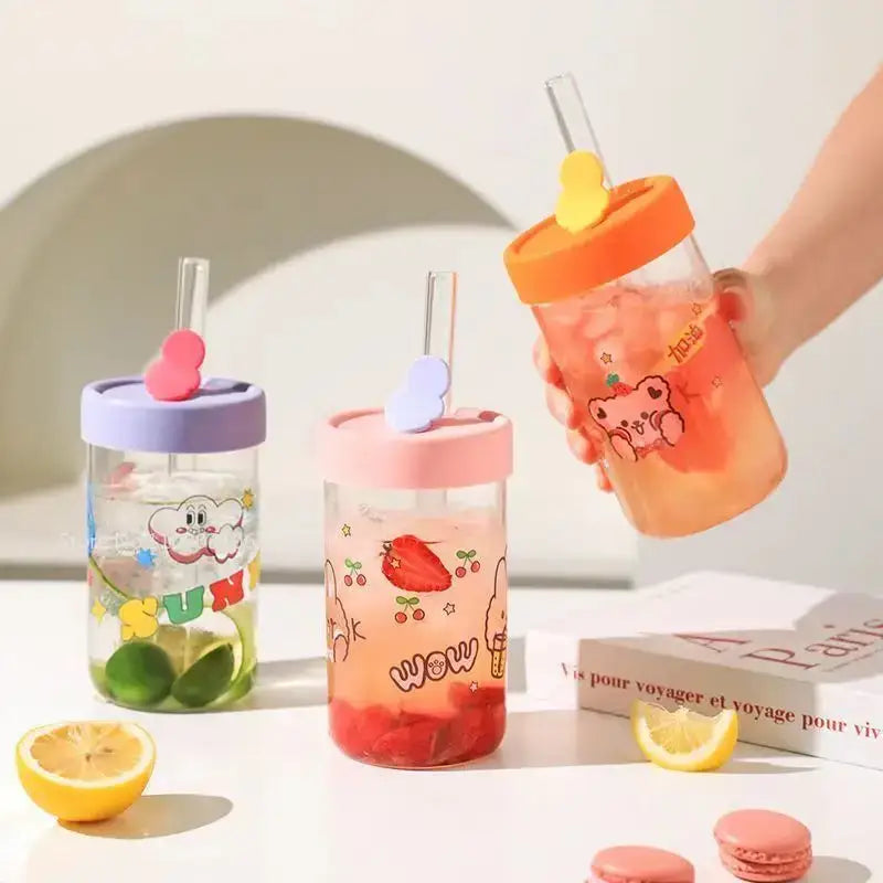 Cute bear cartoon glass cup with orange lid yellow heart straw holder filled with pink liquid decorbites cartoon glass