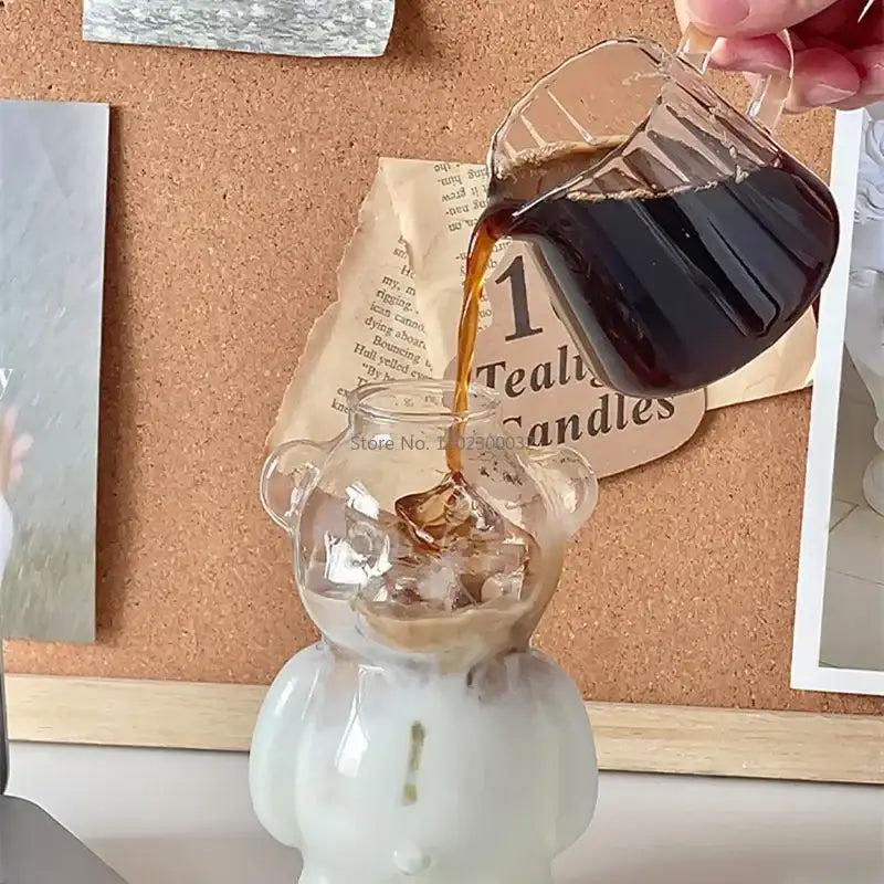 Clear glass bear glass pitcher with handle filled with ice being poured from cute bear glass cups with ceramic base