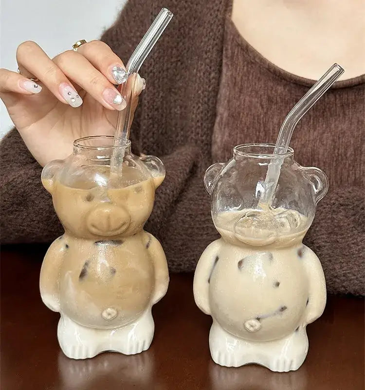 Two clear bear glass cups with white ceramic bases holding iced coffee and transparent straws for kitchen drinkware