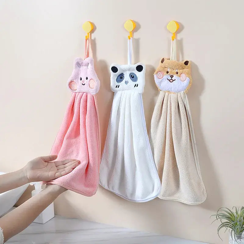 Three plush cartoon animal hand towels in pink, white, and beige with soft texture hanging on yellow hooks for decorbites decor