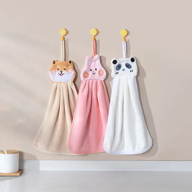 Three plush cartoon animal hand towels in tan shiba inu pink bunny and white panda colors hanging on yellow hooks