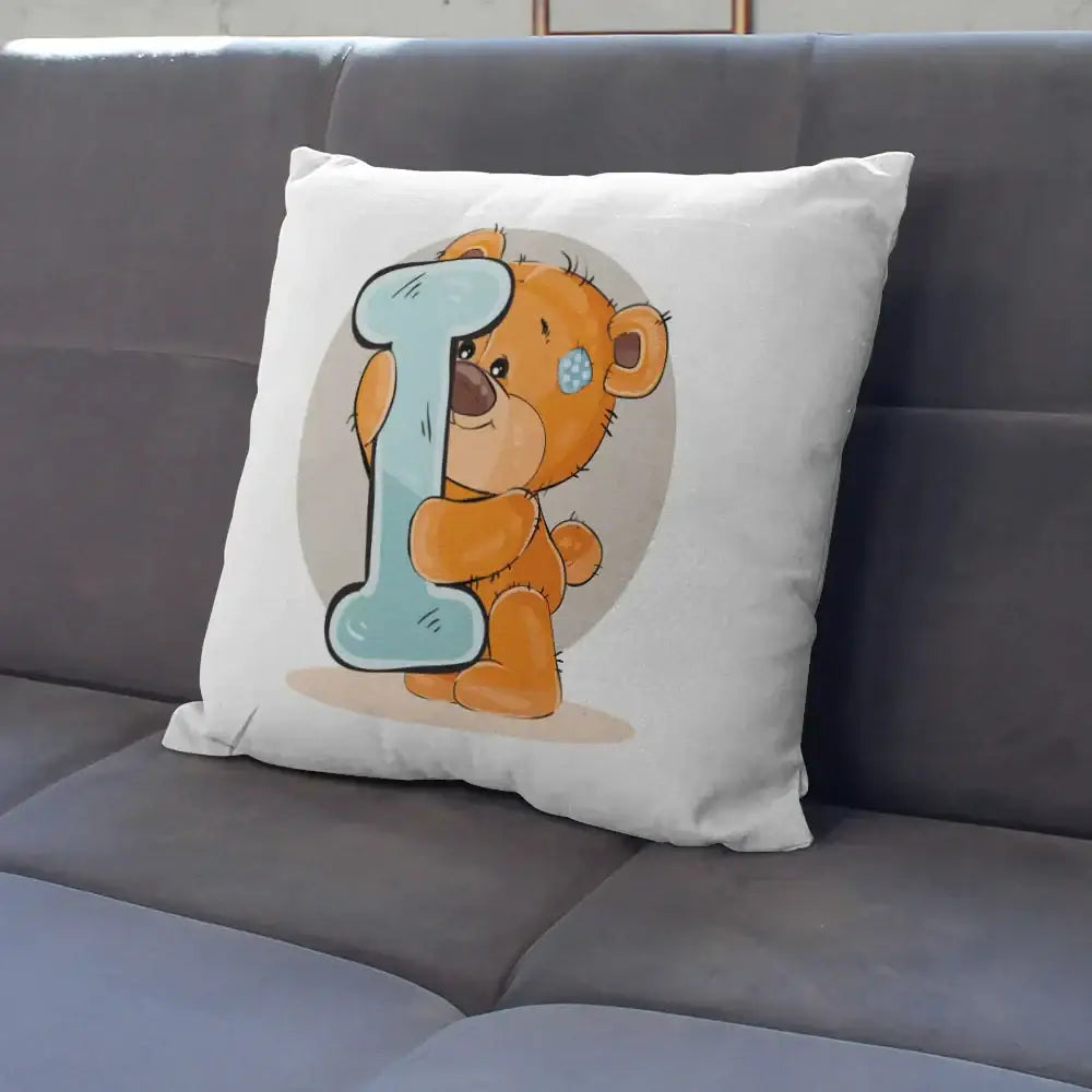 White pillow case with cute cartoon bear animal holding a light blue letter i and wearing a blue polka-dotted eye patch