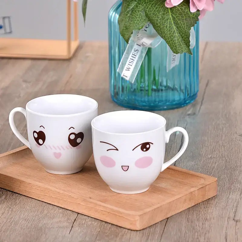 Two white ceramic cartoon coffee mugs with cute winking and smiling faces in a coffee mug set by decorbites