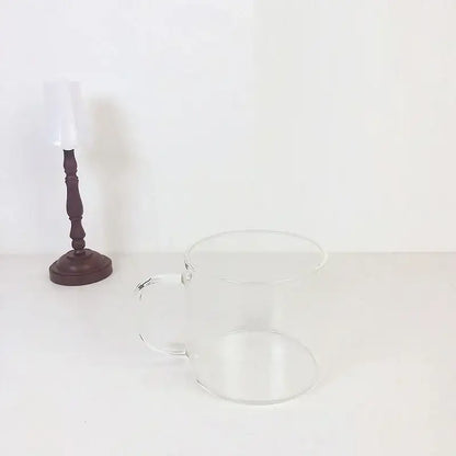 Clear glass mug with smooth handle featuring a cute cartoon cow pattern and spoon lid for dining room use