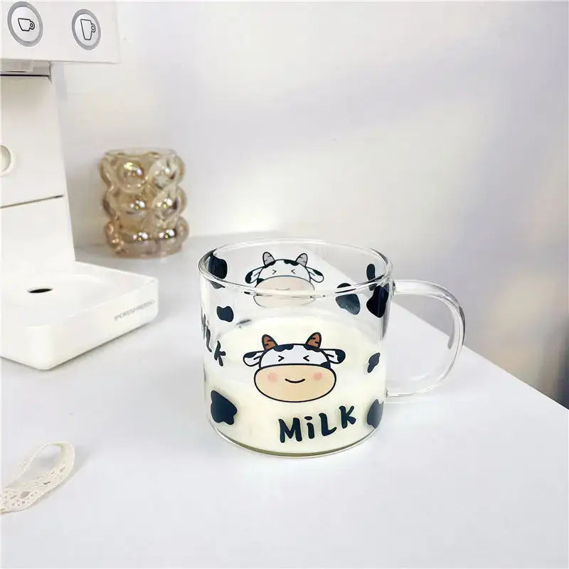 Clear glass mug with black cow pattern and smiling cartoon cow face featuring milk text and a spoon lid for dining room use