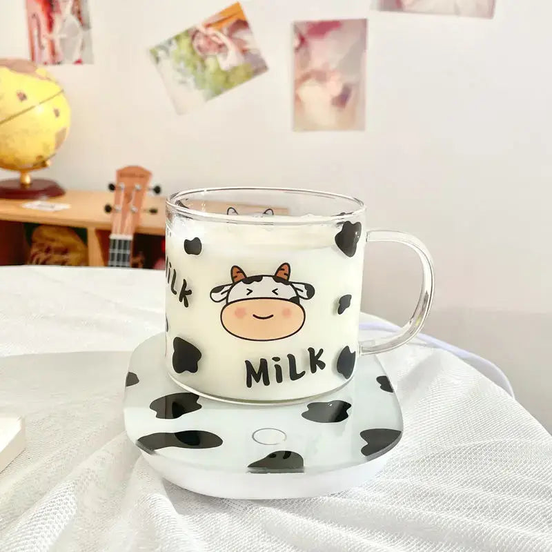 Clear glass mug with black cow pattern and smiling cartoon face featuring milk text and spoon lid for dining room use