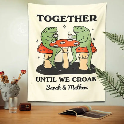 Cream-colored tapestry featuring a cute cartoon frog sipping tea on red mushrooms with cartoon frog moon text decor