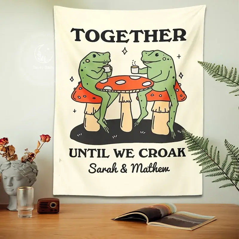 Cream-colored tapestry featuring a cute cartoon frog sipping tea on red mushrooms with cartoon frog moon text decor
