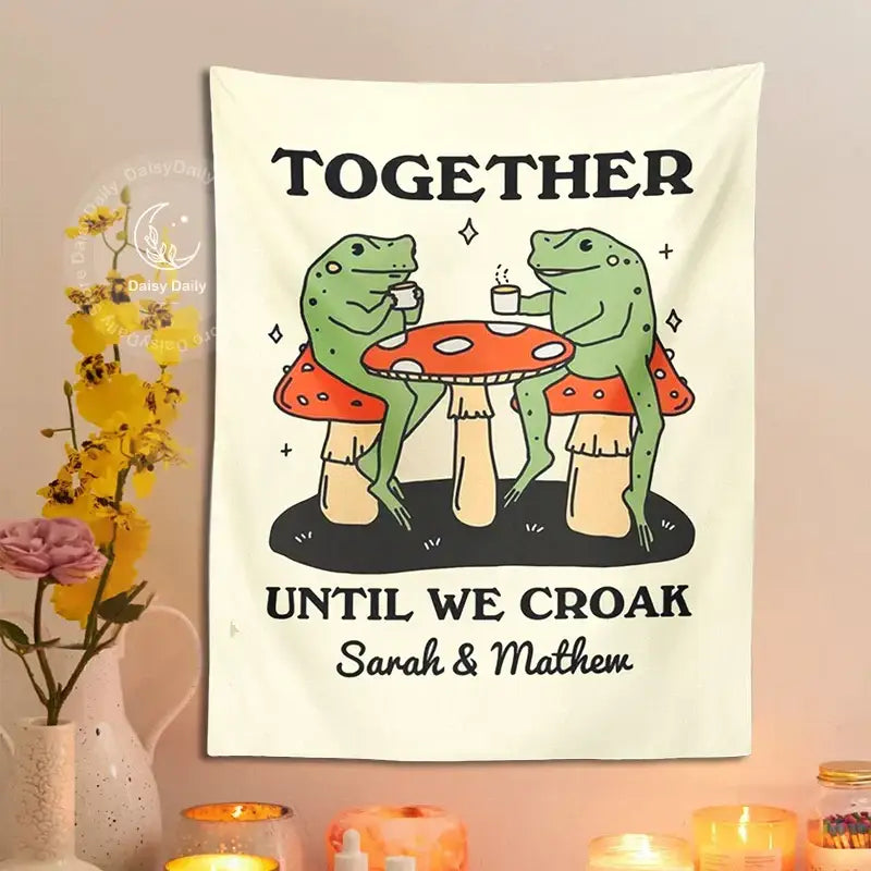 Cream-colored wall tapestry with cute cartoon frog moon design featuring two frogs on mushrooms under personalized text