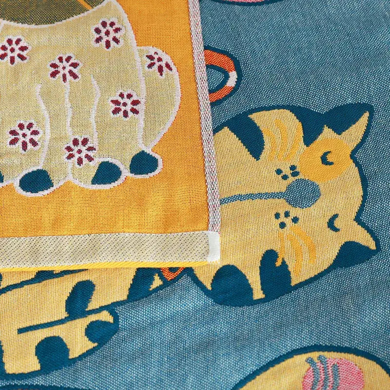 A cute cat bath towel featuring a cheerful yellow cat with dark blue accents and floral pattern on textured fabric