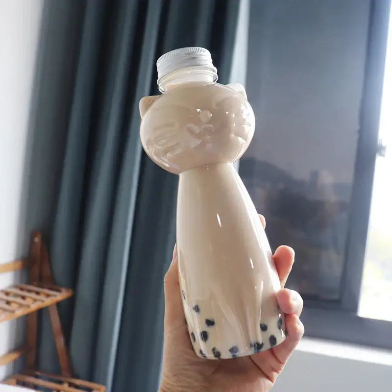 Beige cat beverage bottle made of plastic with silver cap filled with bubble tea and black tapioca pearls bottom