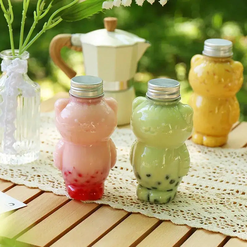 Pastel pink and green bear-shaped glass cat beverage bottles with silver caps for portable coffee and juice use
