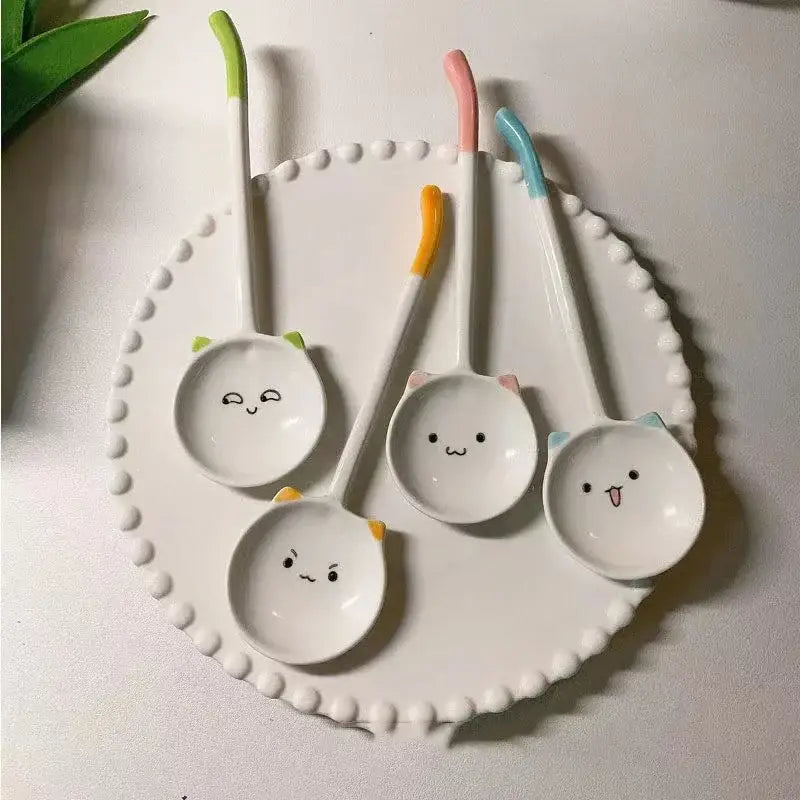 Set of four cute cat ceramic spoons with white cat faces and colorful green pink orange and blue handles for dessert serving