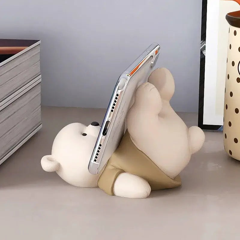 Cute cream ceramic bear cellphone stand in beige with tan shorts holding silver smartphone for bedroom desktop use