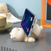 Cream-colored ceramic bear cellphone stand holding a smartphone upright as a cute desktop ornament