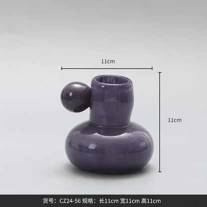A glossy purple ceramic candle holder with a rounded body and cute glass ball decor bites design for living room decor