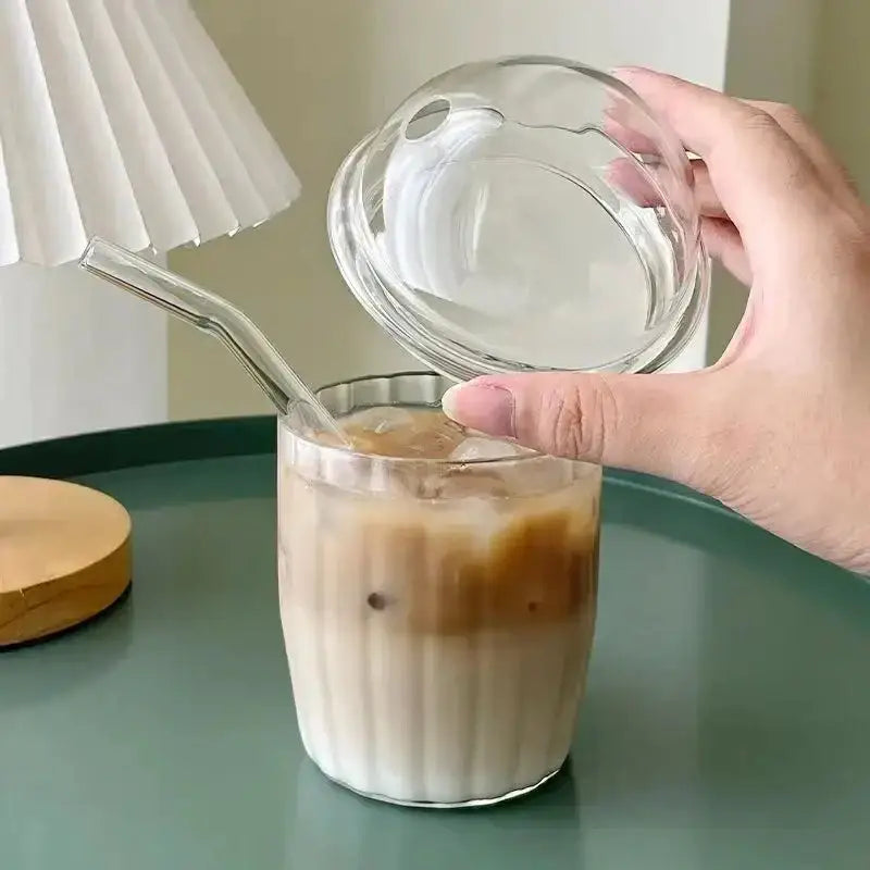 Clear glass cup with fluted design and matching lid filled with iced coffee and pink bow tie decoration