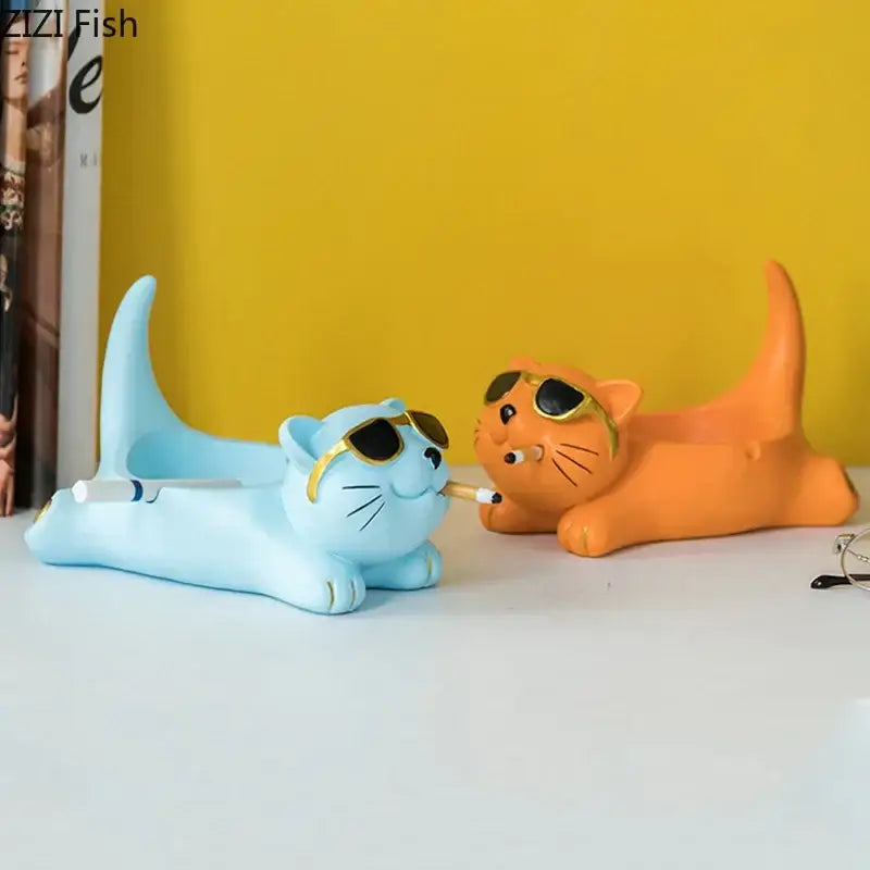 Two whimsical resin cute glasses cat figurines in light blue and orange wearing gold rimmed sunglasses and holding cigarettes