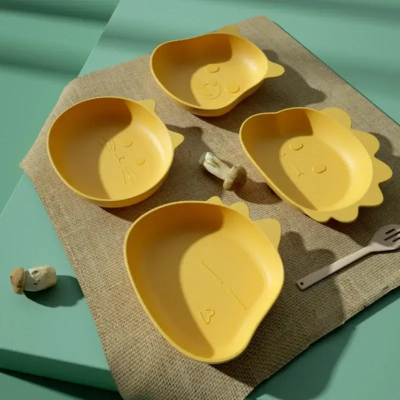 Set of four yellow cat-shaped children plates with molded facial features paired with green bear shape fruit plates