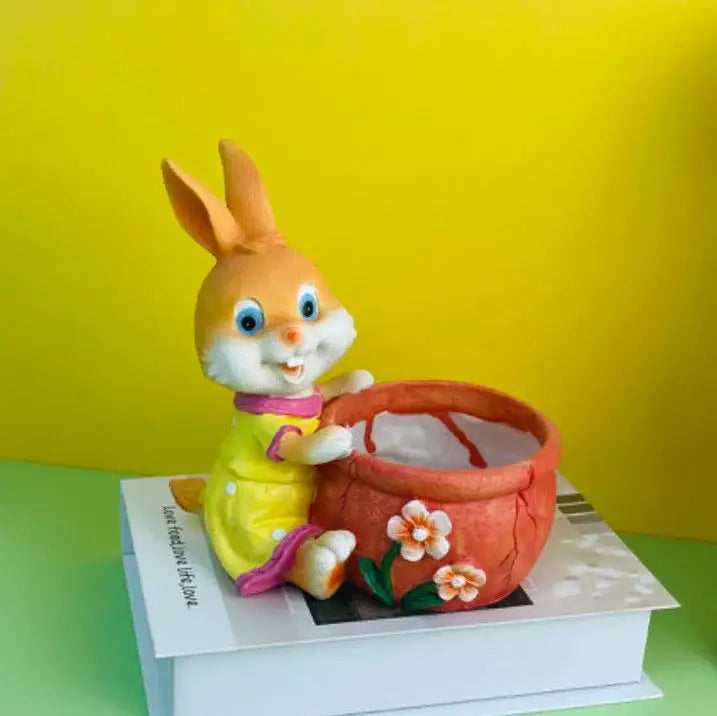 A cheerful orange ceramic bunny rabbit flower pot in a yellow dress holding an ornamental red flower pot