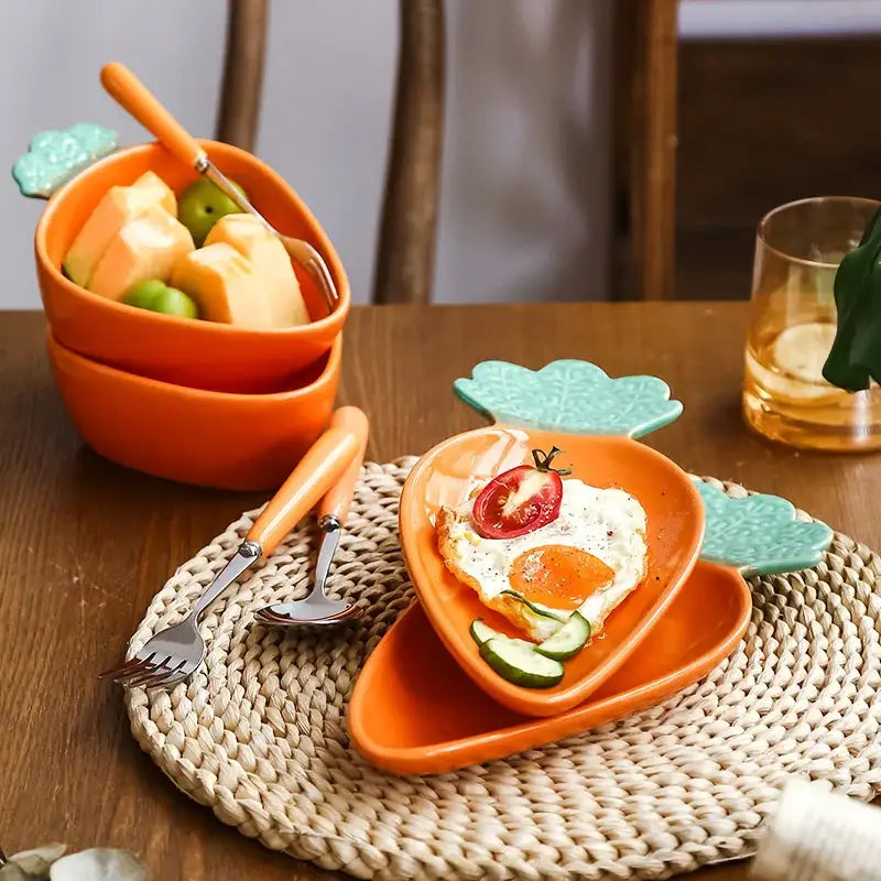 Cute orange and green ceramic tableware set featuring carrot-shaped plates and matching utensils for dining room use