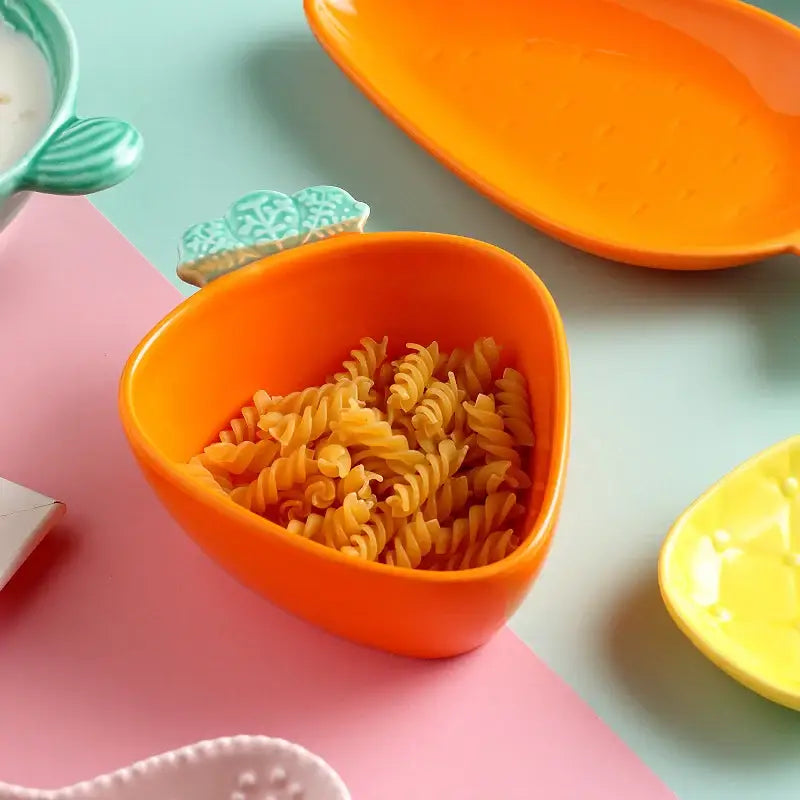 Orange ceramic tableware set featuring a carrot-shaped bowl with green leafy handle detail for dining room use