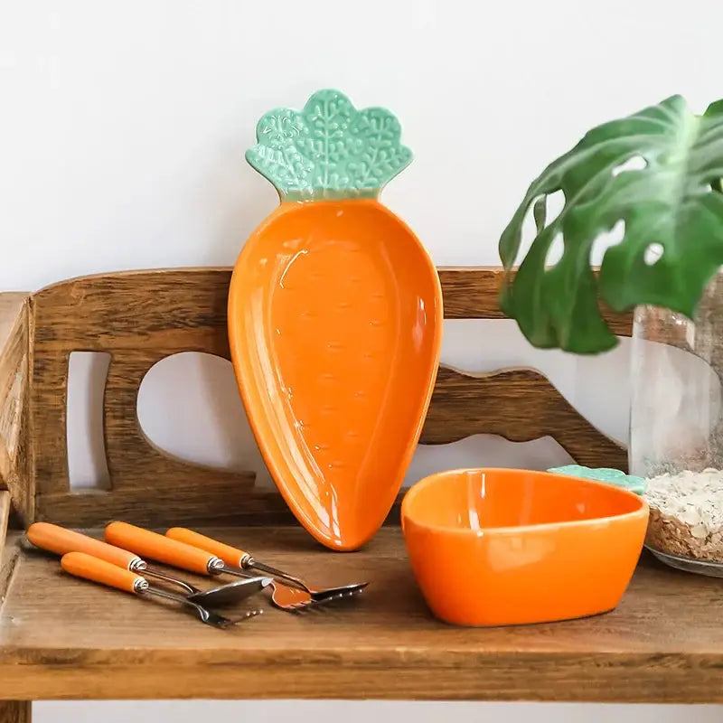 Vibrant orange ceramic tableware set featuring a carrot-shaped serving dish with textured green leafy top for dining room