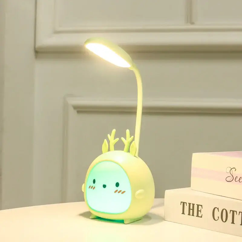 A cute pale yellow decorbites cartoon led desk lamp shaped like a deer with glowing green eyes night light