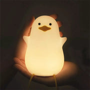 A soft glowing white silicone penguin night light with black eyes and yellow beak usb rechargeable night lamp