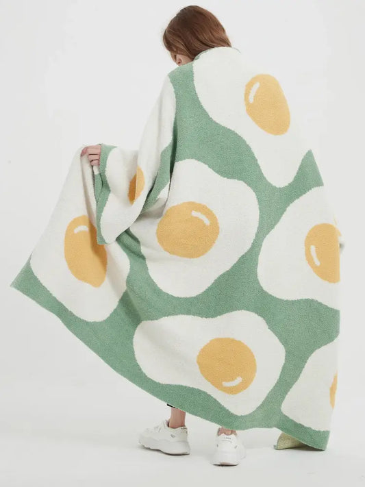 A cozy green knitted throw with a cute poached egg pattern featuring white and yellow fried eggs for bedroom decorbites decor