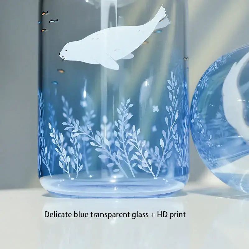 A delicate decorbites blue glass water bottle featuring a white seal hd print among aquatic plants and fish