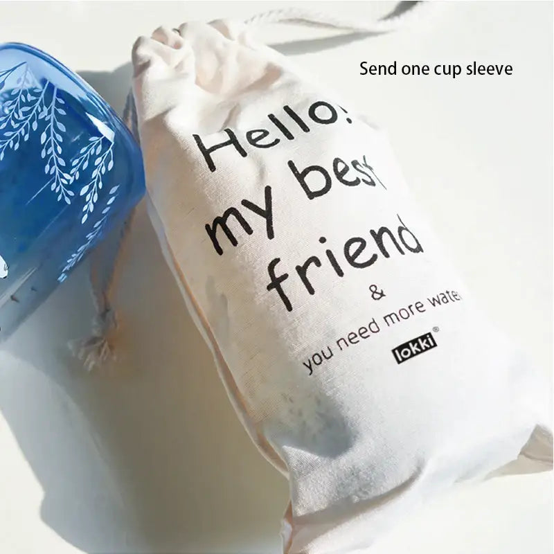 Cream-colored drawstring bag with black text and lokki logo paired with cute polar bear and seal decorbites blue glass water bottle