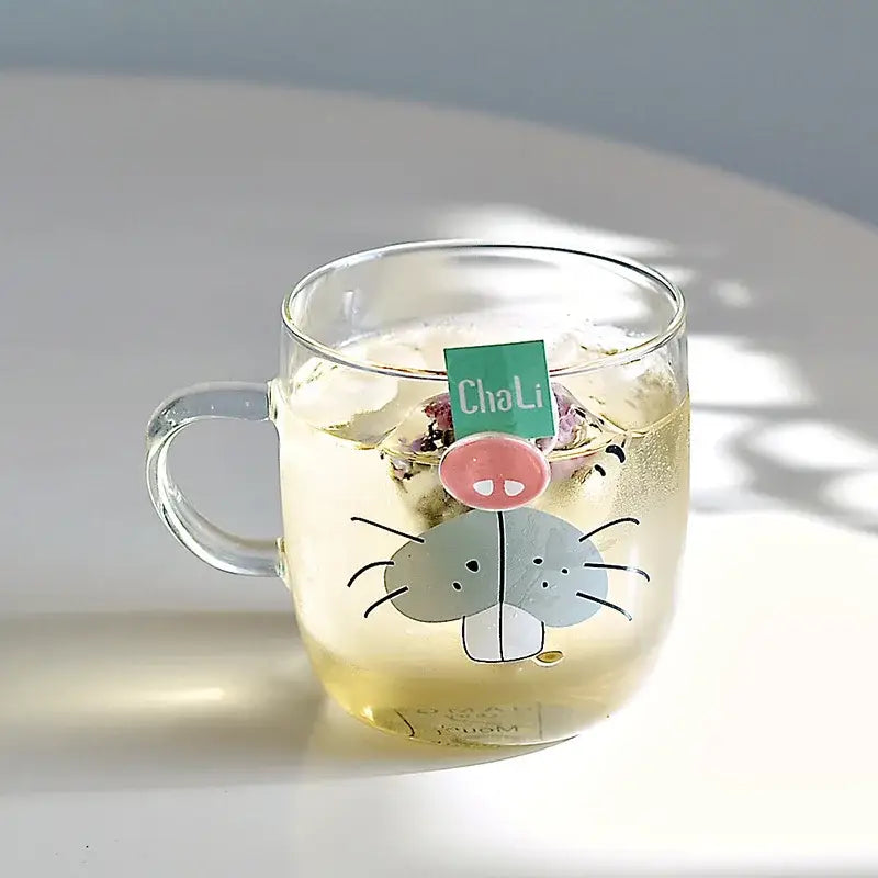 Clear glass coffee mug with cartoon cat design and green chali tea tag inside heat resistant kitchen cup