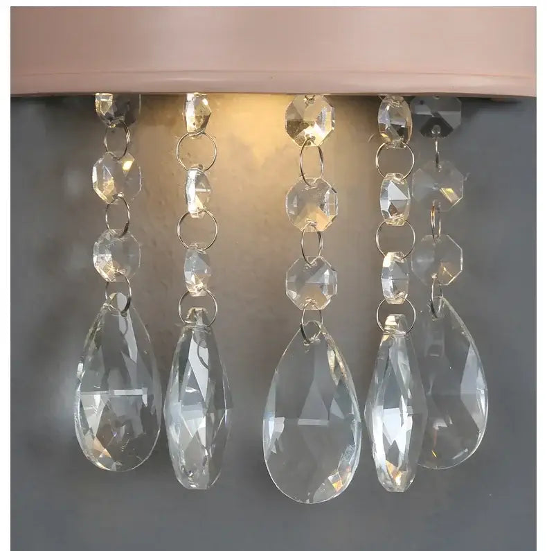 Clear faceted crystal teardrop pendants hanging from silver chains on cute resin crystal pink crown wall sconce decorbites