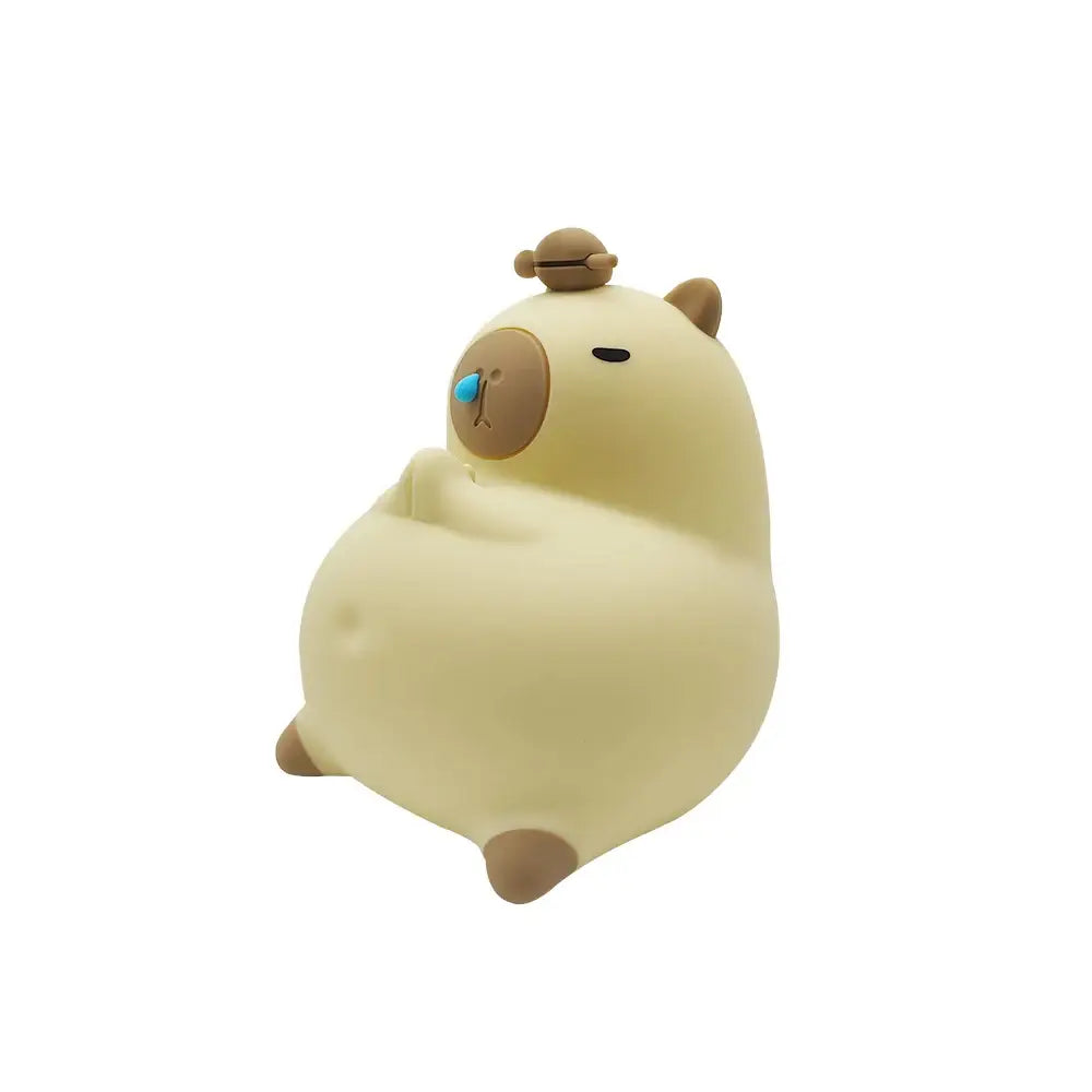 Cream-colored plush-like decorbites capybara silicone night light with brown ears feet blue nose and tiny turtle on head