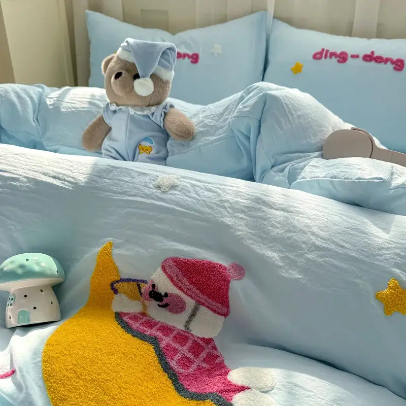 A soft brown plush teddy bear wearing a light blue pajama set with decorbites cartoon embroidery bed sets