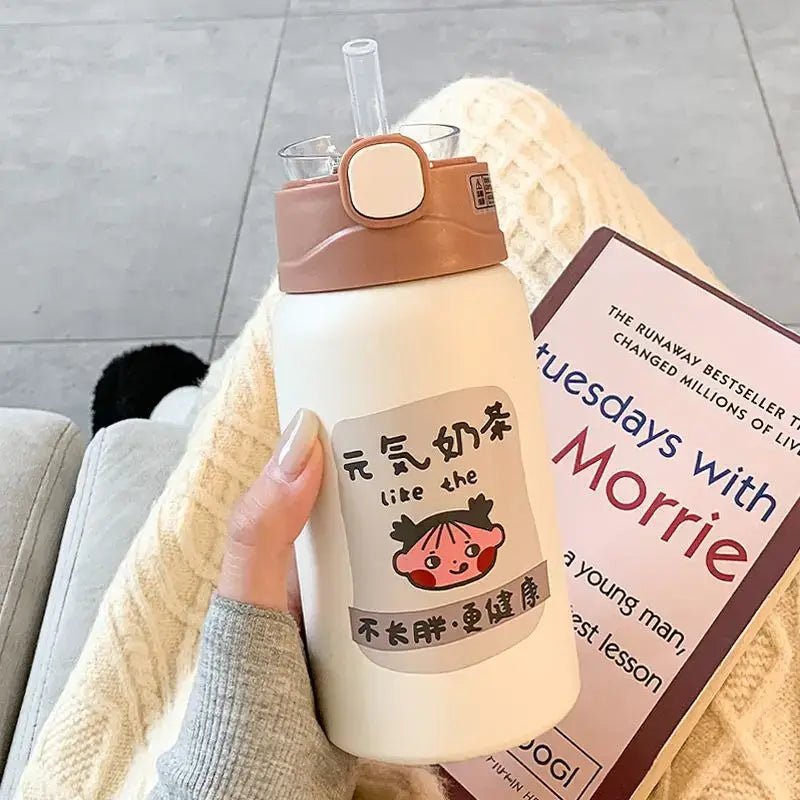Cream-colored insulated thermos cup with tan lid and decorbites cute straw featuring cartoon sticker for travel use