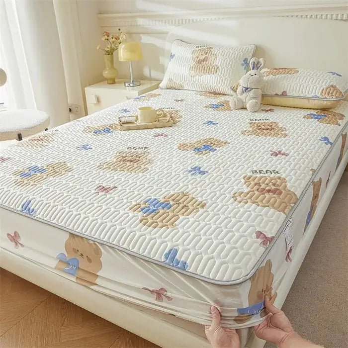 White quilted fitted sheet with a cute cartoon pattern of tan teddy bears and blue bows featuring cooling fabric edges
