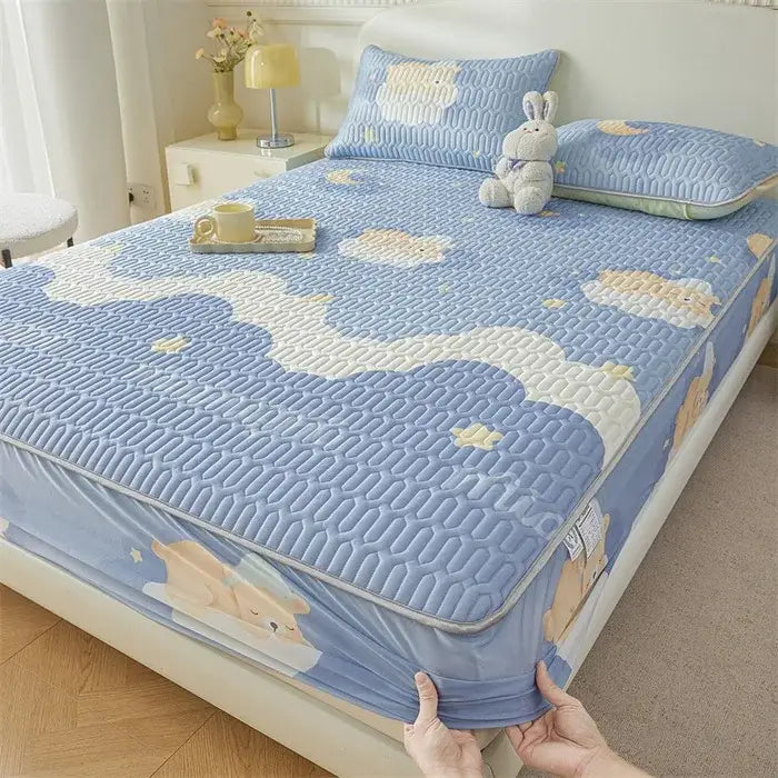Blue quilted fitted sheet with cute cartoon pattern of embroidered bears and clouds featuring a soft textured surface